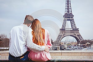 Romantic holidays in France, couple sitting together near Eiffel tower in Paris