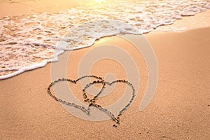 Romantic honeymoon holiday or Valentine`s day on the beach concept with two hearts drawn on the sand, tropical getaway for couple photo