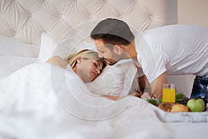 Romantic husband waking wife with breakfast