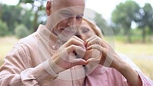Romantic husband and wife showing heart gesture by hands, old age tenderness