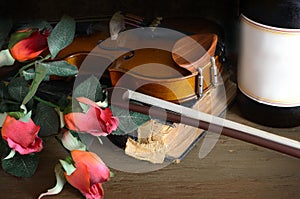 Romantic image of a violin with a glass of red wine and red roses on a rustic wooden table. photo