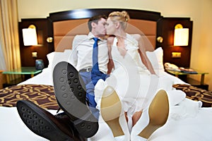 Romantic kiss happy bride and groom in bedroom
