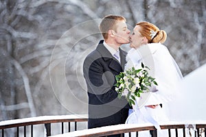 Romantic kiss happy bride and groom on winter day