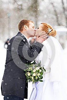 Romantic kiss happy bride and groom on winter