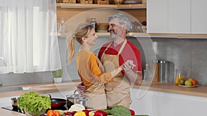 Romantic leisure at home. Happy middle aged loving spouses dancing together at kitchen and flirting, free space