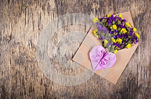 Romantic letter. Flowers in a paper envelope and a paper heart of origami.