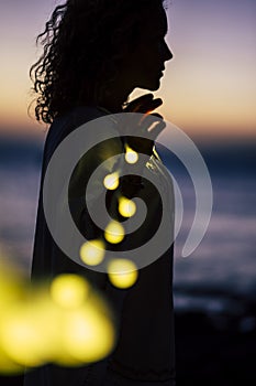 Romantic life concept with standing lady and yellow bulb romance light - defocused natural outdoor background with coloured sunset