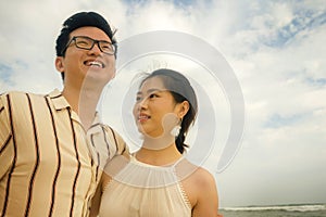Romantic lifestyle portrait of young Asian Korean couple in love enjoying holiday on beautiful beach walking together by the sea
