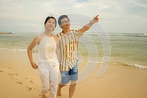 Romantic lifestyle portrait of young Asian Korean couple in love enjoying holiday on beautiful beach walking together by the sea