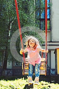 Romantic little girl on the swing, sweet dreams. childhood daydream. freedom. Playground in park. Small kid playing in