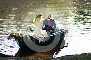 Romantic love story in boat. Woman with wreath and white dress. European tradition