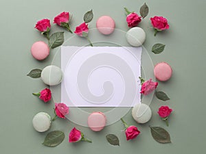 Romantic lovely frame from macarons and roses on green background. Flat lay. Top view