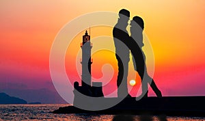 Romantic lovers with lighthouse on a background.  Lighthouse of Chania at summer sunset , Crete , Greece