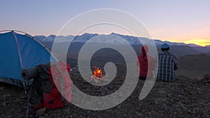 Romantic loving tourist couple at camping, tent with bonfire on top of mountains at sunset