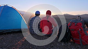 Romantic loving tourist couple at camping, tent on rocky top of mountains at sunset