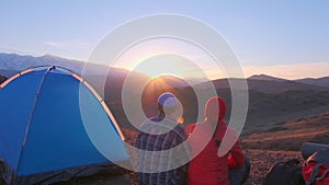 Romantic loving tourist couple at camping, tent on rocky top of mountains at sunset