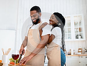 Romantic Lunch. Happy Black Wife Cuddling Husband While They Cooking Food Together