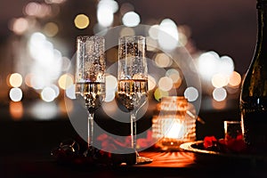 Romantic luxury evening with champagne setting with two glasses, rose petails and candles