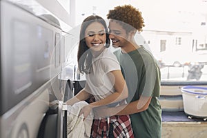Romantic Man Hugging Wife Loading Washing Machine At Laundromat Room