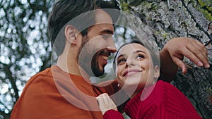Romantic man hugging woman leaning on tree closeup. Loving young couple laughing