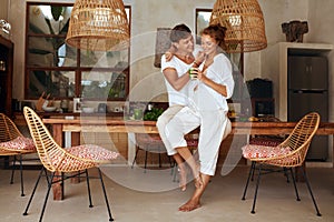 Romantic Man And Woman At Kitchen. Young Couple Standing Together With Glass Of Detox Cocktail In Hand.