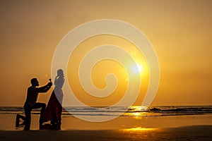 Romantic marriage proposal at the seaside at sunset on the beach sea. Young couple in love female said yes to offer of