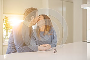 Romantic middle age couple sitting together and kissing at home