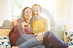 Romantic middle age couple watching tv on the sofa at home