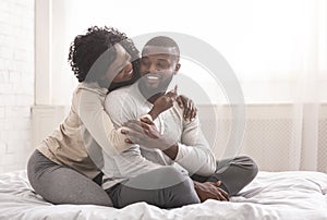 Romantic millennial couple cuddling while sitting in bed in morning