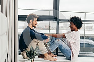 Romantic mixed race couple standing by the window thinking about their future.