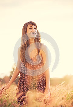 Romantic Model in Sun Dress in Golden Field at Sunset