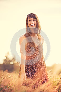 Romantic Model in Sun Dress in Golden Field at Sunset