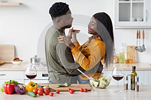 Romantic Moments. Happy Black Couple Dancing And Drinking Red Wine In Kitchen