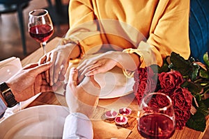 Romantic moments. Young man holding hands of his girlfriend in restaurant