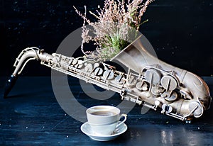 Romantic morning with coffee cup and flowers in saxophone