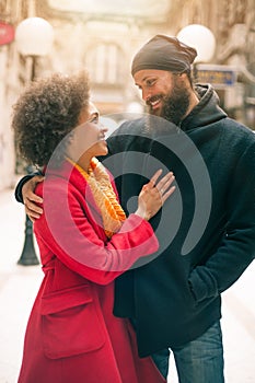 Romantic multiethnic couple in love hugging on the street