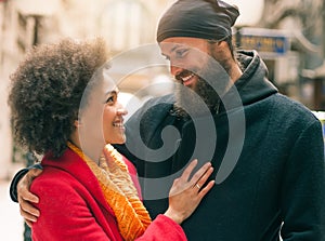 Romantic multiethnic couple in love hugging on the street