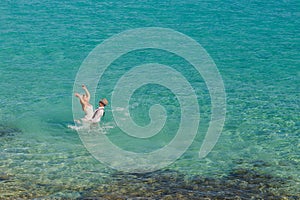 Romantic newly-married couple enjoying a summer vacation. Young groom lifting his bride in sea.