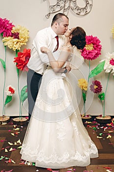 Romantic newlywed couple kissing after first dance at wedding reception, handsome groom hugging sensual bride, wedding moment