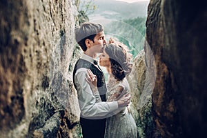 Romantic newlywed couple posing in sunset lights on majestic roc