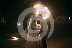 Romantic newlyweds kissing at night in front of flaming heart