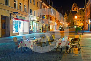 Romantic night scene of street cafe with two tables and old street with citylights on background, Fussen, Germany