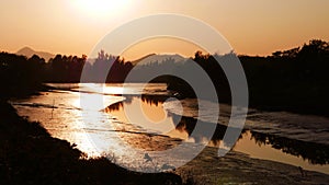 romantic orange sunset with small curve river and tree reflection