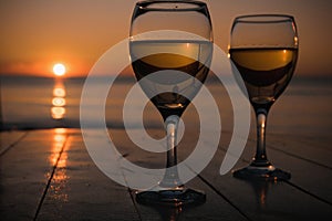 Romantic outdoor activity. Two glasses with white wine in an outdoor restaurant with sunset sea view, relaxation concept for two