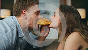 Romantic pair eating croissant home zoom on. Loving man woman face bitting bun