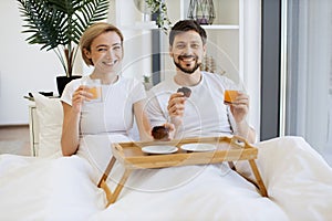 Romantic partners enjoying breakfast time in comfy bed