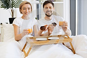 Romantic partners enjoying breakfast time in comfy bed