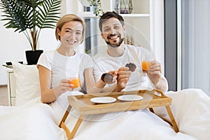 Romantic partners enjoying breakfast time in comfy bed