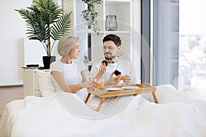 Romantic partners enjoying breakfast time in comfy bed