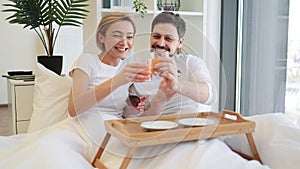 Romantic partners enjoying breakfast time in comfy bed